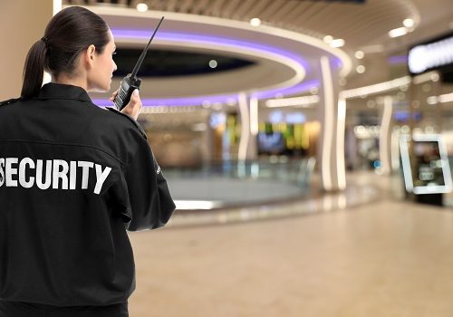 Security guard using portable radio transmitter in shopping mall, space for text